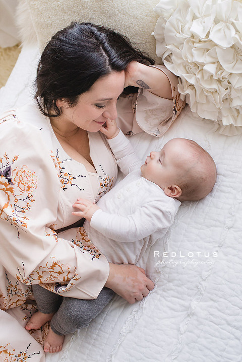 mother and baby portraits laying on a bed neutral colors