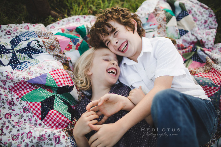 children laughing on a quilt family photography