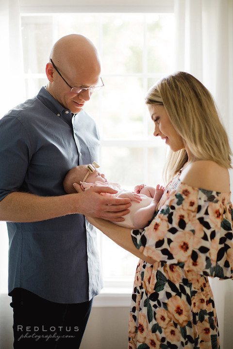 newborn photographer in home session mom and dad by window