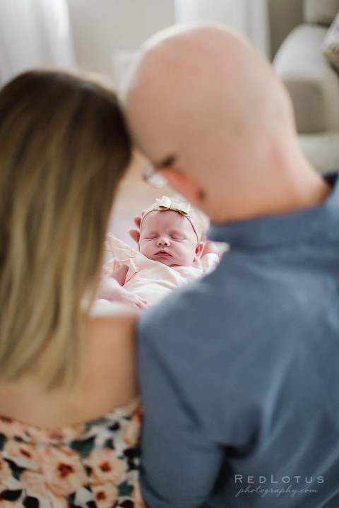 cute newborn photography pose mom and dad looking at baby