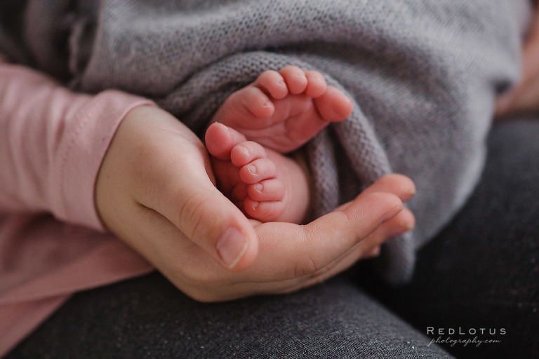 baby feet held by sibling hand
