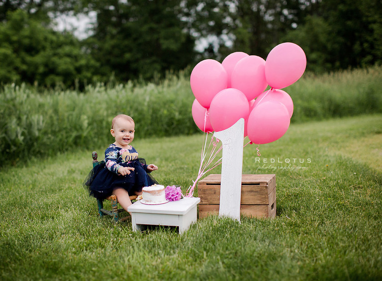 first birthday photos cake smash session outdoors girl with cake and balloons