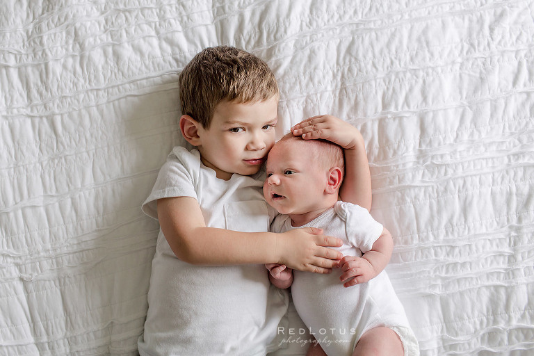 newborn sibling photos baby and brother laying on bed