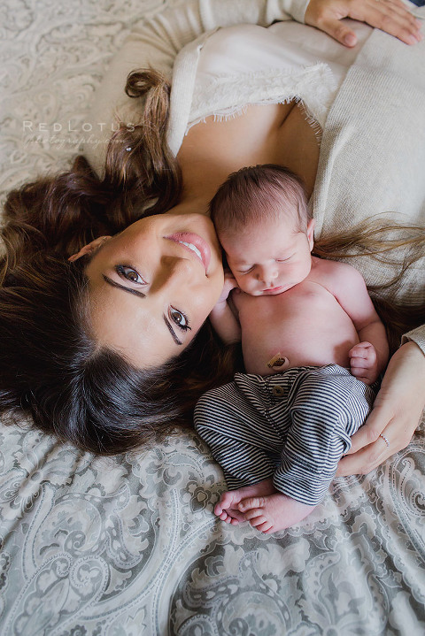 newborn baby and mother pose laying down