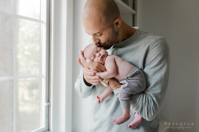 newborn baby and dad pose kiss