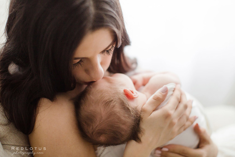 mother kissing newborn baby