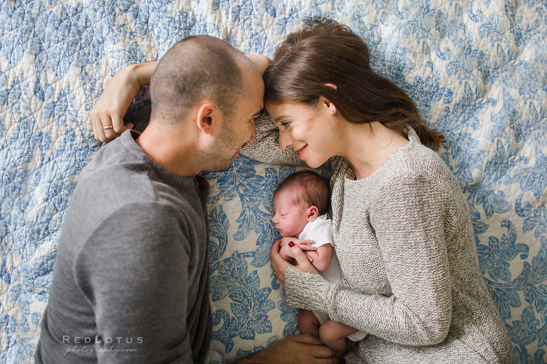 home newborn session parents and baby pose on bed lifestyle photography