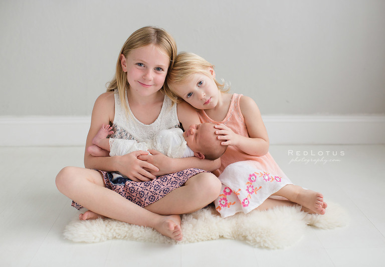 newborn and siblings pose baby girl and sisters