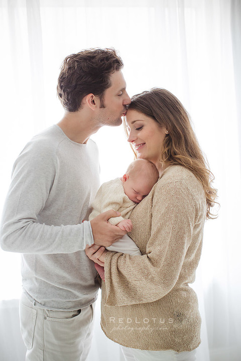 newborn photography pose parents baby kiss on forehead Pittsburgh studio light and airy neutral colors