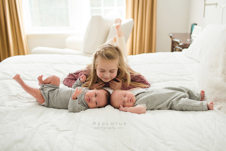 newborn twin and sibling pose laying on bed