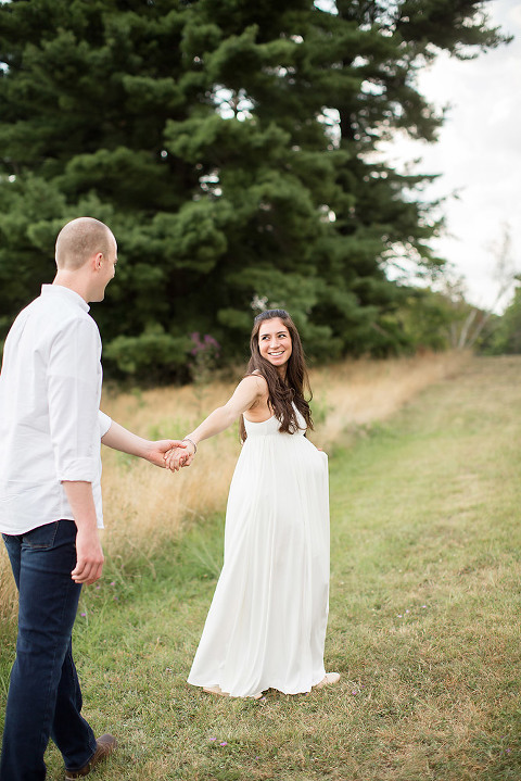 maternity photos couple outdoors white dress holding hands smiling
