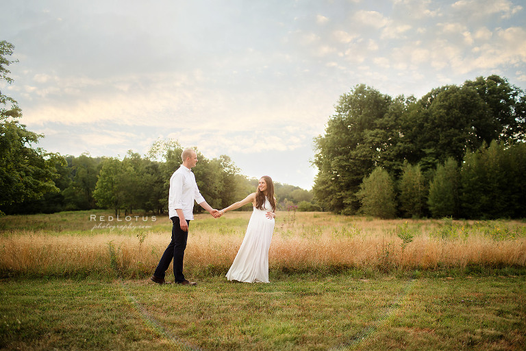 maternity photos outdoors grassy field couple holding hands