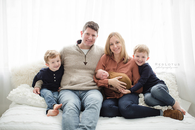 newborn photographer Pittsburgh family pose casual on bed with backlighting light and airy neutral white studio