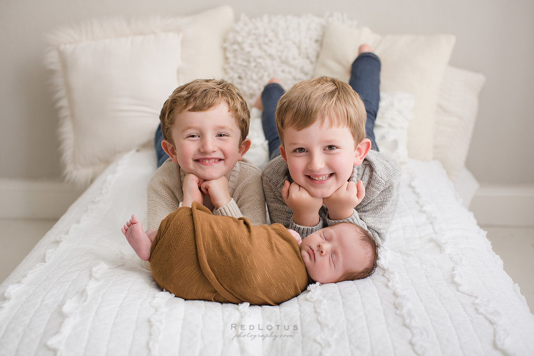 newborn photography baby and siblings safe pose on bed