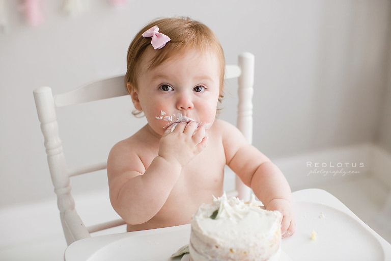 baby smashing cake with hands one year birthday photos