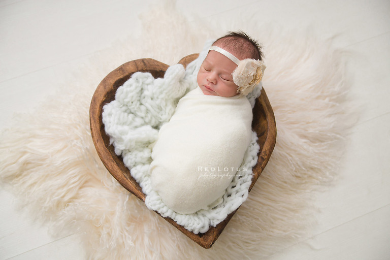 newborn in a wooden heart bowl prop