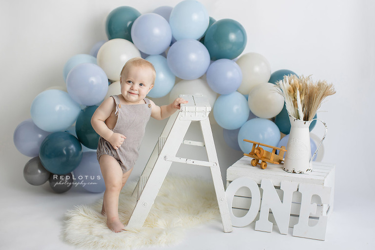 first birthday photos boy with blue balloon garland