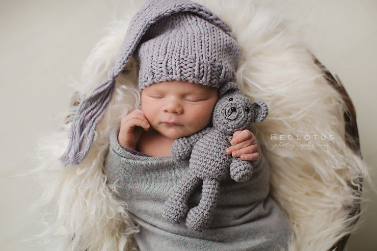newborn baby with sleeping cap and teddy bear