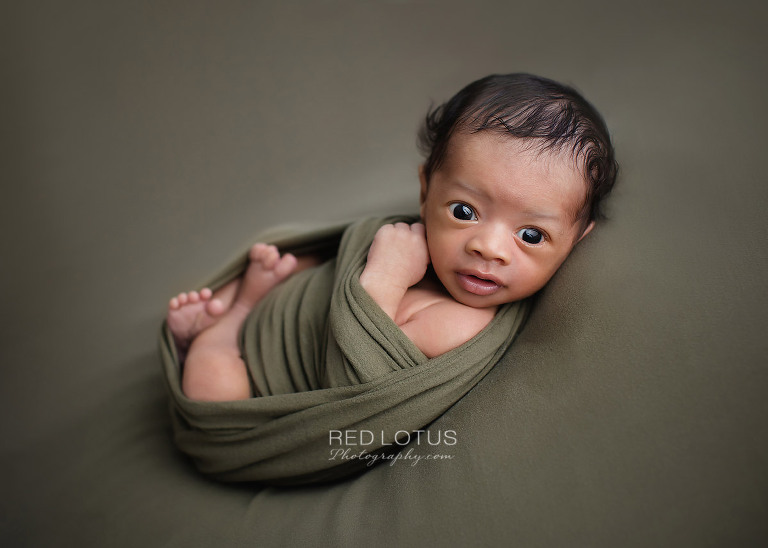newborn photo awake baby eyes open with olive green blanket and wrap