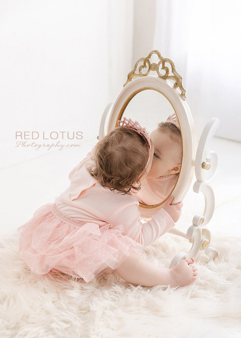 toddler girl kissing her own reflection in the mirror