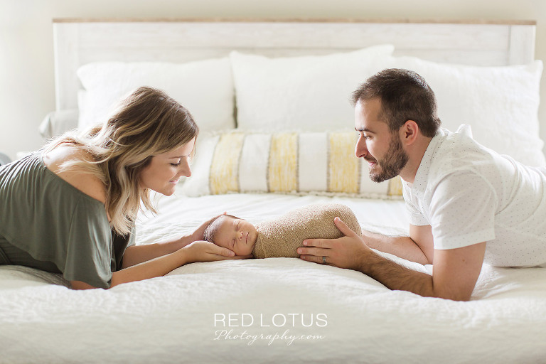 home newborn session parents holding baby and smiling