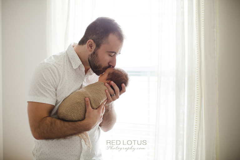 home newborn session dad kissing baby on the forehead