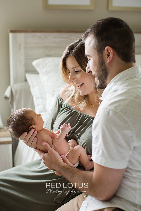 home newborn session parents holding infant and smiling