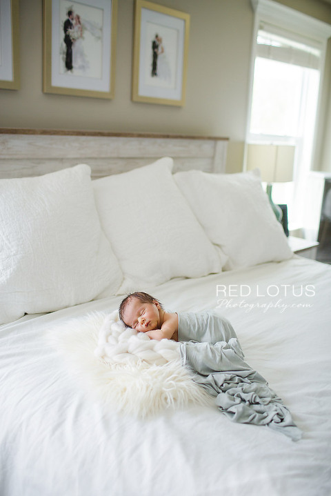home newborn session wide shot of baby sleeping on the bed