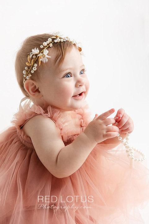 one year old toddler girl wearing blush tulle dress