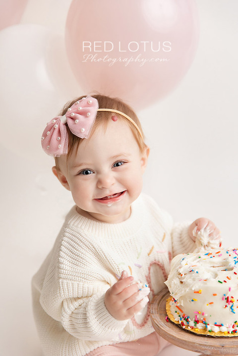 one year old toddler girl with smash cake smiling