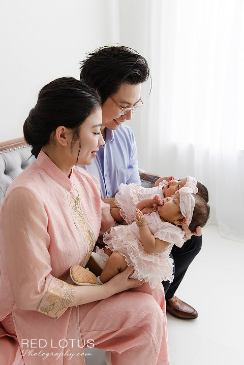 young asian couple gazing lovingly at their twin baby newborn girls