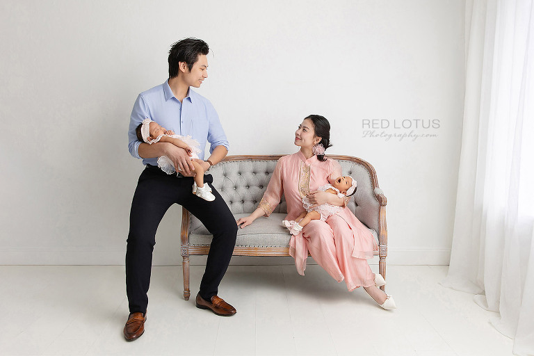 young asian couple holding their twin baby girls gazing lovingly at each other