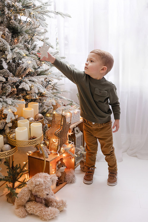 little boy putting ornament on a Christmas tree